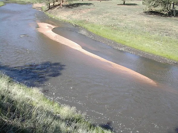 The South Platte River - Circa 2002: The South Platte River runs grey from the silt, ash and charcoal embers. The banks were lined with black charcoal up to an inch in diameter.